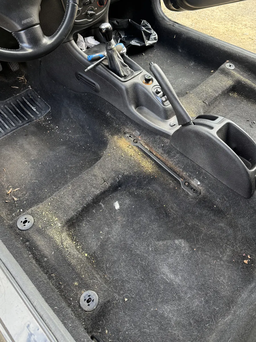 Plancher conducteur d'une Peugeot 206 couvert de poussière et de débris